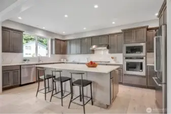 Kitchen with oversized island & stainless steel appliances. Previous built Peak house. Finishes may be different.