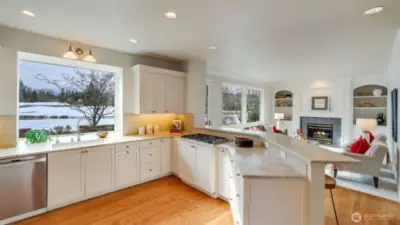 Renovated kitchen showcases exquisite cream cabinetry, raised eating bar for 4, updated lighting and tranquil views of the golf course.