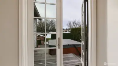 French doors from den lead to deck with secluded hot tub