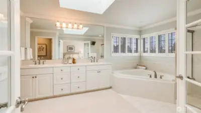 Primary bathroom features a jetted soaking tub, dual sinks, and skylight