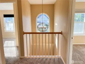 Appealing light fixture, arched window and railing overlooking the front foyer between the first & second bedrooms.