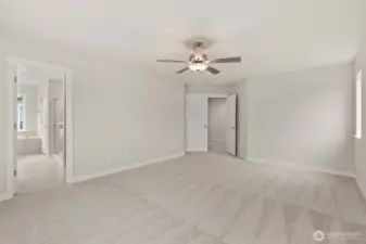 Spacious primary bedroom features vaulted ceilings, large windows for natural light, and a ceiling fan for added comfort.