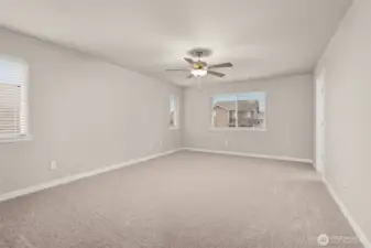 Spacious primary bedroom features vaulted ceilings, large windows for natural light, and a ceiling fan for added comfort.