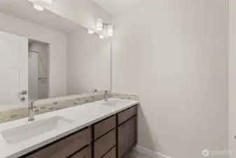 Upstairs hall bath features a dual vanity with quartz counters and backsplash.