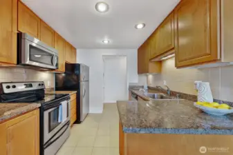 Well-appointed kitchen with granite breakfast bar, tile floors and stainless appliances.