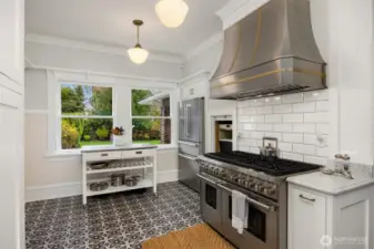 Designed for both beauty and performance, the kitchen showcases a professional-grade 8-burner double range/oven beneath a custom hood, surrounded by crisp cabinetry and historic trim—an inspired setting for serious cooks and casual meals alike.