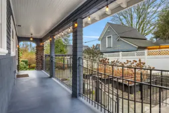 A covered side porch enhances everyday living, providing a sheltered transition between indoor spaces and the garden below.