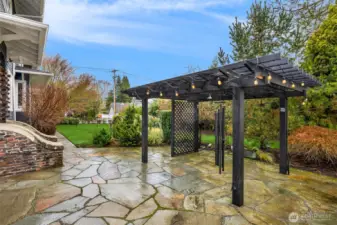 The backyard is unexpectedly expansive and beautifully curated, featuring a stone patio, pergola with ambient lighting, manicured lawn, and layered garden beds. Fully enclosed and thoughtfully designed, it offers privacy, versatility, and year-round enjoyment — equally suited for entertaining or quiet moments at home.