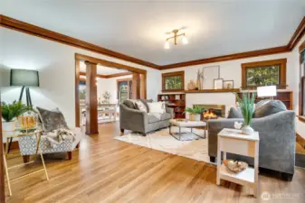 The living room glows with freshly painted walls in a timeless color palette, crown molding, and picture rails that pay tribute to the expert craftsmanship of the era. The space feels perfectly preserved, especially now that the hardwood floors have been beautifully restored to their original shine.