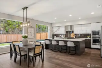 The heart of the home; featuring a spacious quartz prep island with breakfast bar seating, stainless steel appliances, and expansive windows that fill the space with natural light.