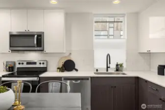Kitchen features stainless steel appliances, window treatments and a quartz countertop.