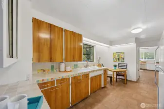 Hand crafted artisan tiles made by a local Olympia artist frame the tile kitchen counters and backsplash. The clean lines of the high-gloss, face-frame cabinets evoke the vibe of the era. Eating nook and garden window too!