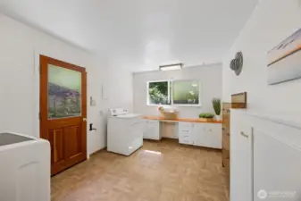 Beyond the kitchen find an extra large mud/laundry room, sewing space or garden prep area with clever shoe storage cabinets and more. This side door leads up a few short steps to the level parking area/shop and well.
