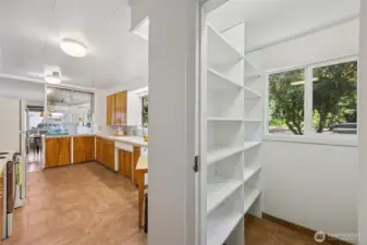 A look back down the kitchen from the laundry area shows a large, natural light, walk-in pantry between the kitchen and mud room space.