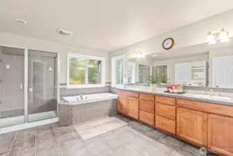 spacious primary bathroom with soaking jacuzzi tub, duel vanity, and 3/4 shower