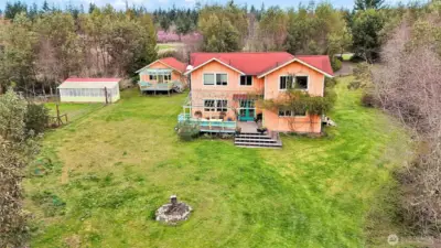 Back view of main residence, guest house, greenhouse and fenced vegetable garden