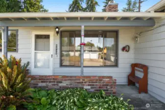 Covered front porch entry with retro brick flower planter.