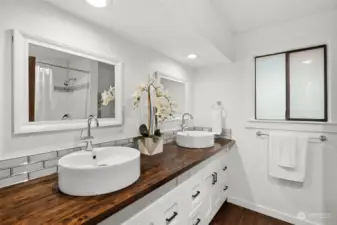 Elegantly remodeled with glass subway tile, raised vessels and white shaker style cabinetry, you will love the ensuite primary bathroom.