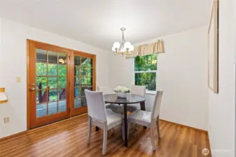 Dining area off the kitchen with French doors and large windows, bringing in natural light and forested views.