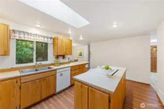 Light-filled kitchen with skylight, abundant cabinet storage, and a window overlooking the trees.