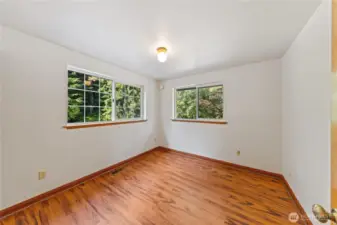 Second upper-level guest bedroom with double windows for natural light and peaceful views of the surrounding evergreens.