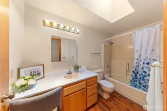 Full guest bath with skylight, tub/shower combo, and extended vanity—conveniently located between the two upper bedrooms.