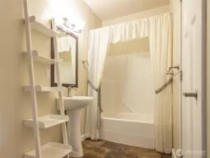 The main bath is large and built in white shelving gives you plenty of storage for towels and other bath items.