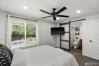 A stylish, modern barn door provides a chic entry to the en suite.