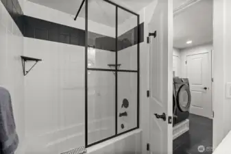 Enjoy a stylish tile-surround tub complemented by a chic matte black-framed glass wall, offering a clean, sophisticated look.