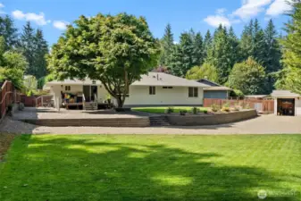 The yard features a modern block wall, creating a sharp visual separation between the upper and lower lawn areas.