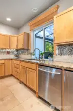 Updated kitchen with solid surface stone counters, tile backsplash, undercabinet lighting, gas range. Serene views from kitchen, dining, living.