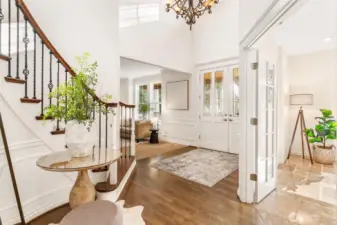 Bright, open-concept foyer with white wainscoting and polished hardwood flooring.