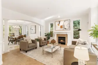 Sophisticated living space featuring a gas fireplace, large windows, and an arched transition to the dining area.