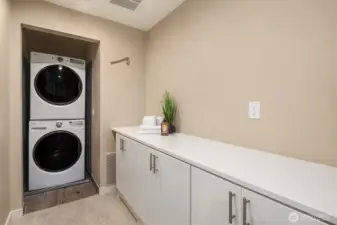 Generous upper-level laundry room with abundant storage and stacked washer/dryer