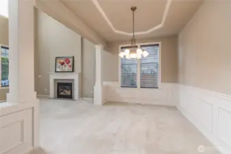 Classy dining room boasts a coffered ceiling, architectural columns and wainscoting