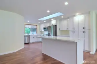 Kitchen is a cooks delight with Quartz countertops and Quartz Island, stainless appliances, wall of pantry cabinets, and a skylight! Notice the vinyl plank flooring.