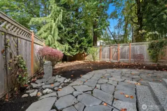 Private back yard with stone patio and newer fencing.
