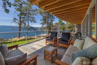 The covered terrace extends the living space outdoors, offering comfortable seating and sweeping views across Haro Strait toward the Olympic Mountains—perfect for year-round outdoor enjoyment.