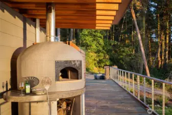 The outdoor entertaining terrace features a custom wood-fired pizza oven, perfect for gatherings and alfresco dining while enjoying the serene setting of this luxury waterfront estate on San Juan Island.