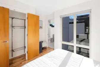 A look toward the en-suite bath, with a generous closet and another large window for natural light.