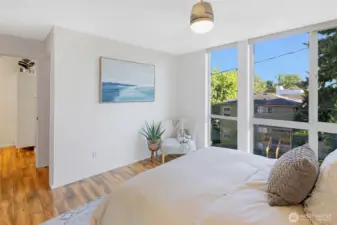 The primary suite feels open and inviting with expansive windows overlooking the treetops. From this view, you can see down into the hallway, with the ¾ bath tucked just around the corner.