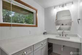 Bright and inviting primary bathroom features a large window that fills the space with natural light, beautifully light fixtures, and a stylish vanity with ADA accessibility for added comfort and convenience