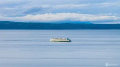 A stunning view of the Edmonds-Kingston ferry making its way across Puget Sound, captured from the waterfront with sparkling water and surrounding scenery.