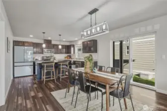 The heart of the home shines with quartz countertops, rich cabinetry, stainless steel appliances, and a large island perfect for gathering. An open dining space flows effortlessly to the sliding glass door and fenced yard, making indoor-outdoor entertaining a breeze.