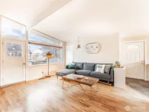Bright living room with original hardwood floors and wood-burning fireplace.
