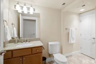 Guest bathroom with a spacious glass walk-in shower, ceramic tile shower and countertop, Kohler fixtures, and a convenient linen closet for added storage.