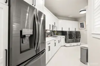 A large mud room with numerous cabinets and extra refridgerator space.