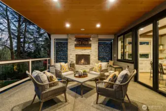 A covered patio with a gas fireplace and an inset TV mount above the fireplace (behind the art).