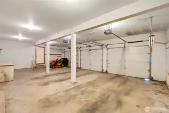 Spacious three-car garage with a working sit-on tractor and large functional freezer included.