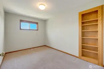 Versatile room off garage with hidden closet behind built-in shelves.
